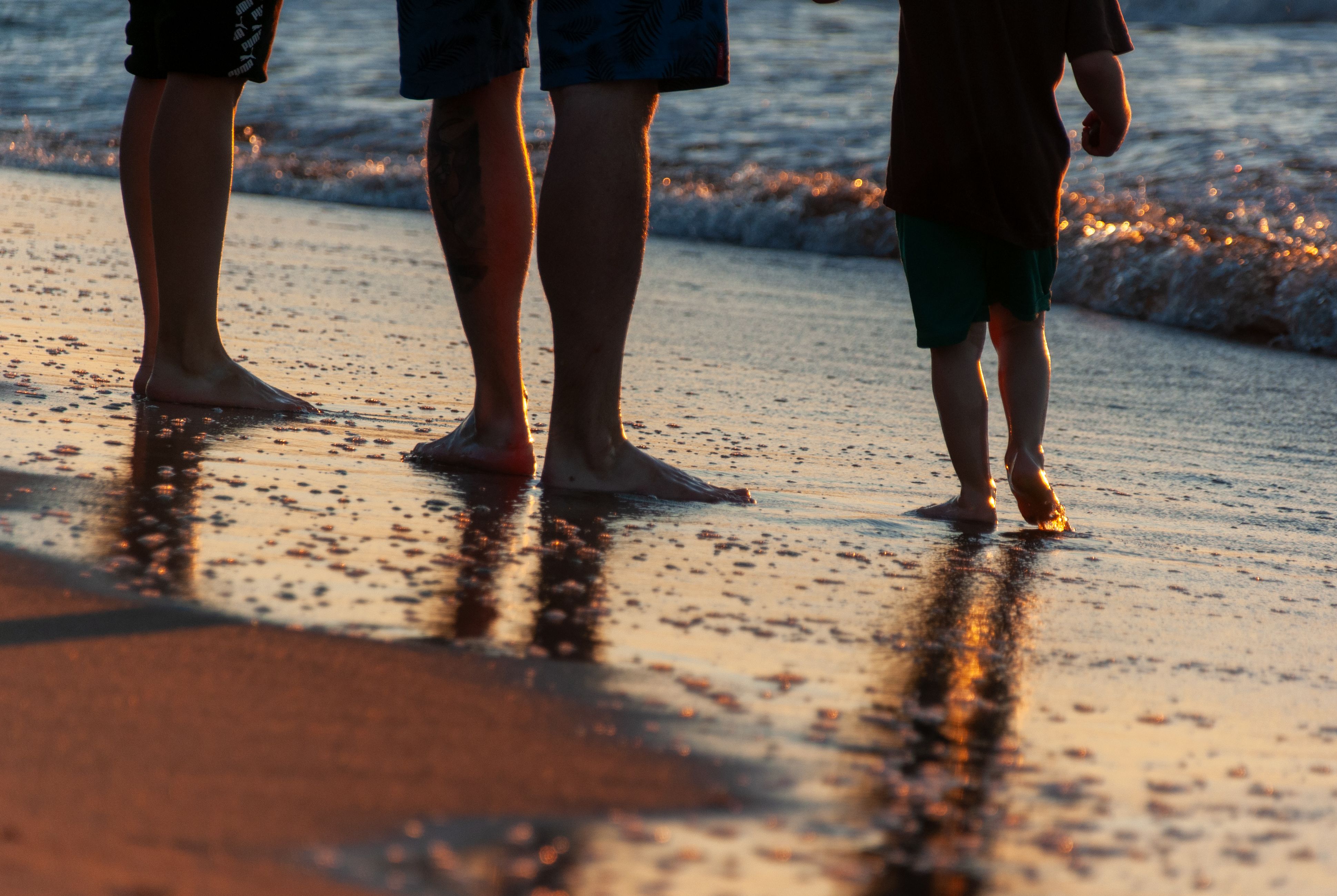 Family standing together at the shore at sunset