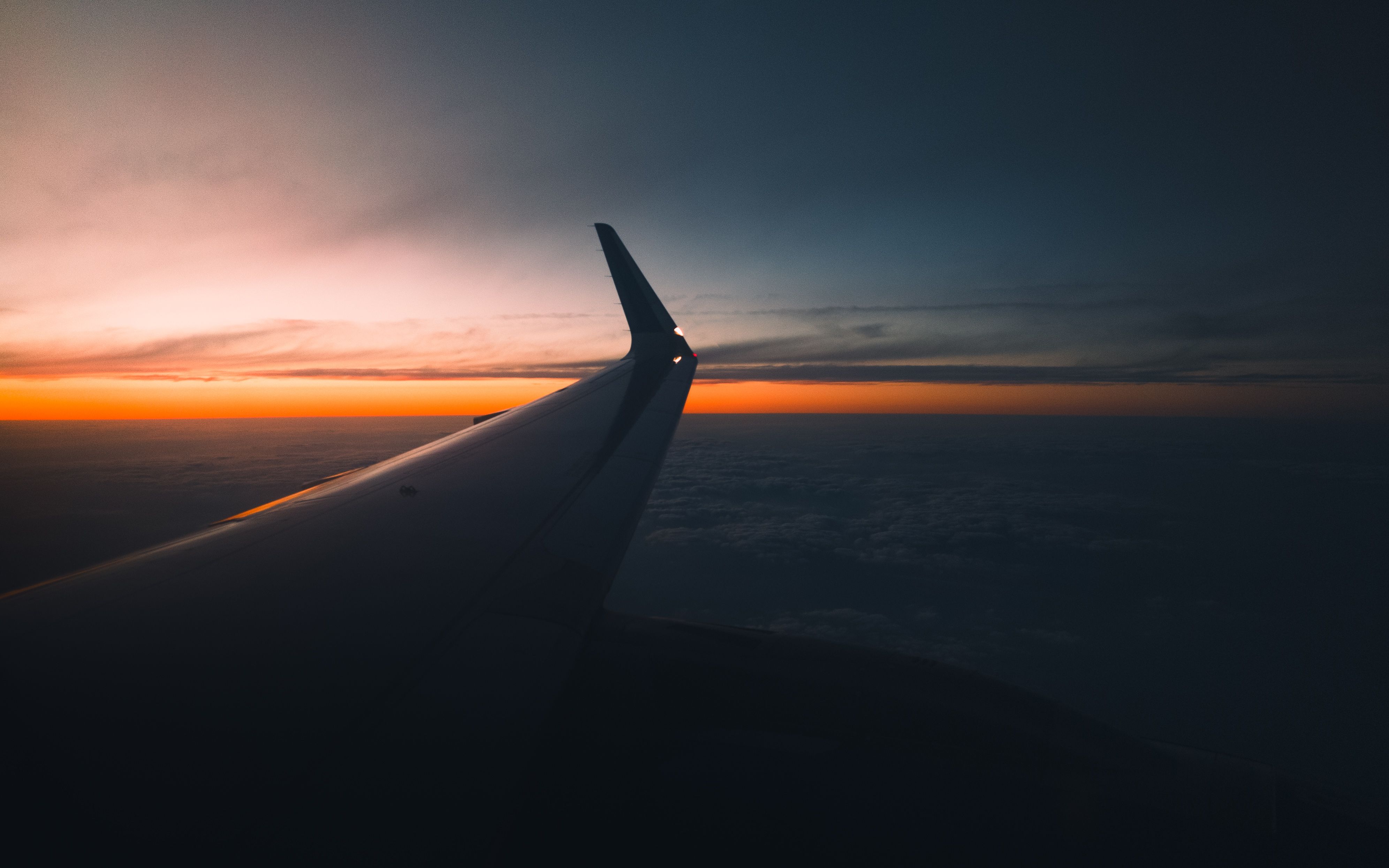 Airplane wing above clouds at sunset